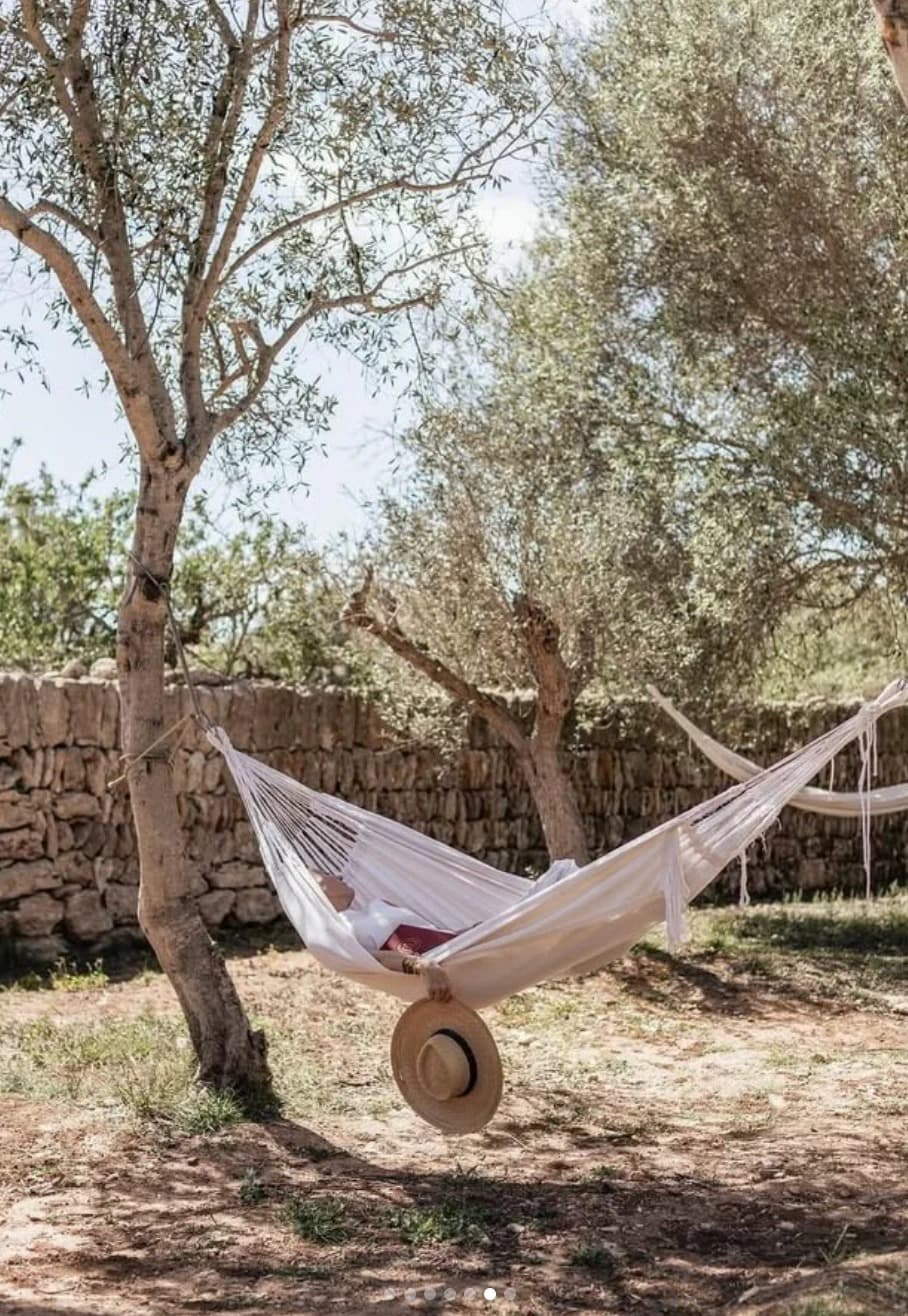 A hammock strung between olive trees at Cal Reiet, a sun hat resting below